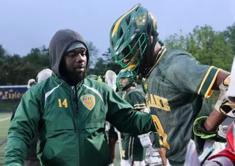 Coach Maxwell speaks to a player on the football field.
